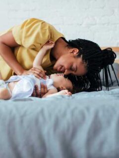 mom and baby playing on bed