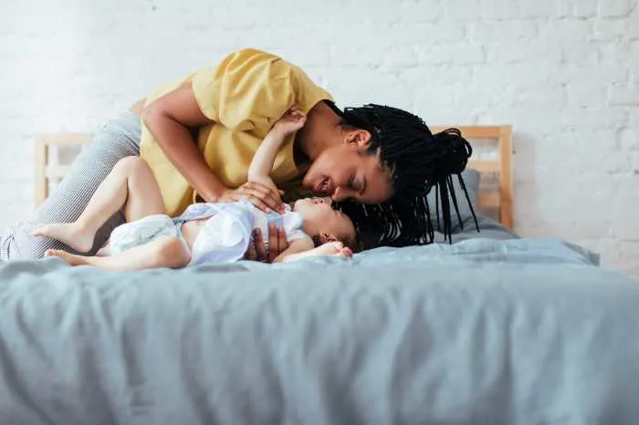 Mom playing with baby on bed