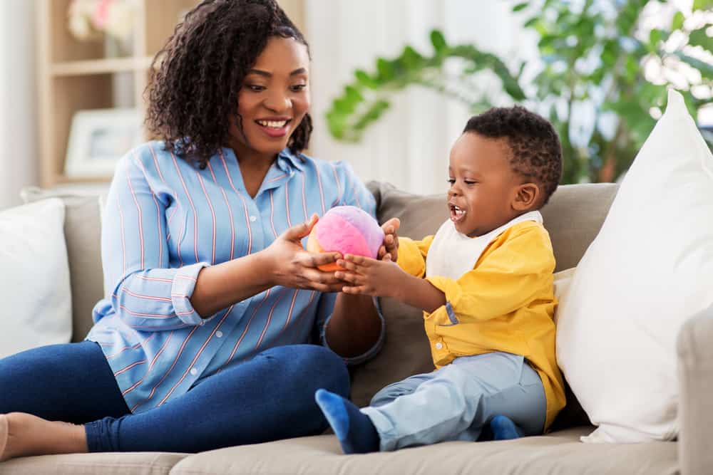 happy african american mom and and baby playing with a ball