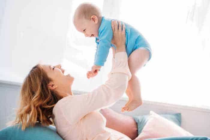 mom holding up baby and smiling