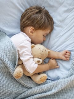 toddler sleeping in bed with stuffed animal