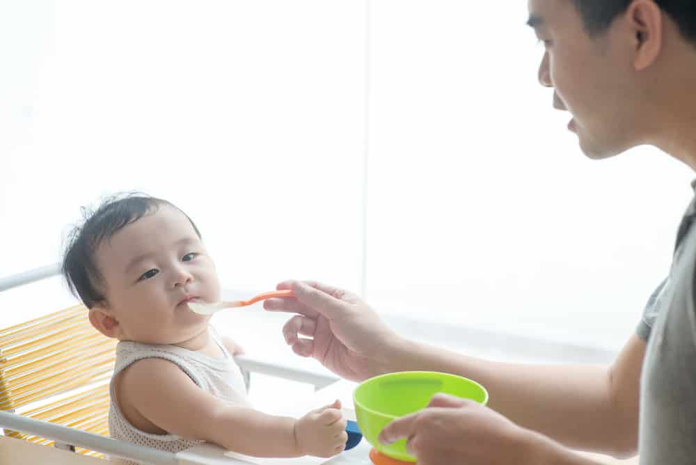 baby being fed by dad with a spoon