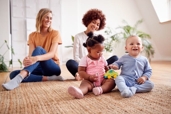 moms sitting with toddlers playing