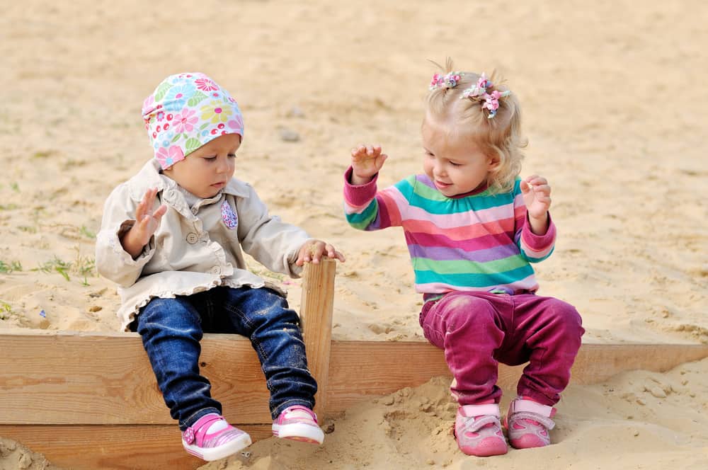 Toddlers playing in the sand together