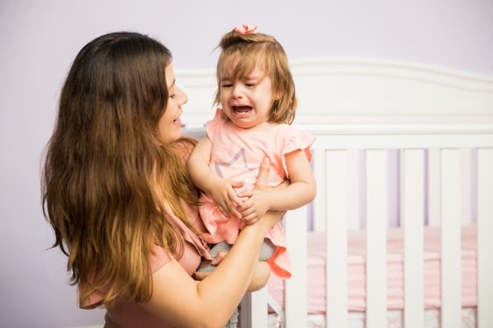 mom holding toddler crying