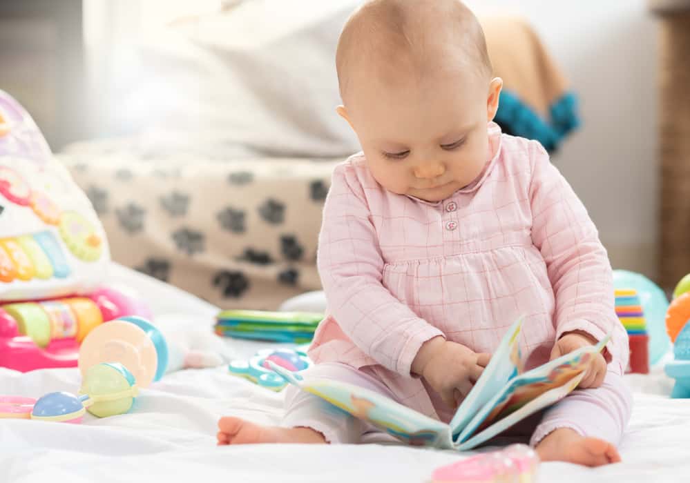 Portrait of little cute baby girl sitting and holding a book, light effect