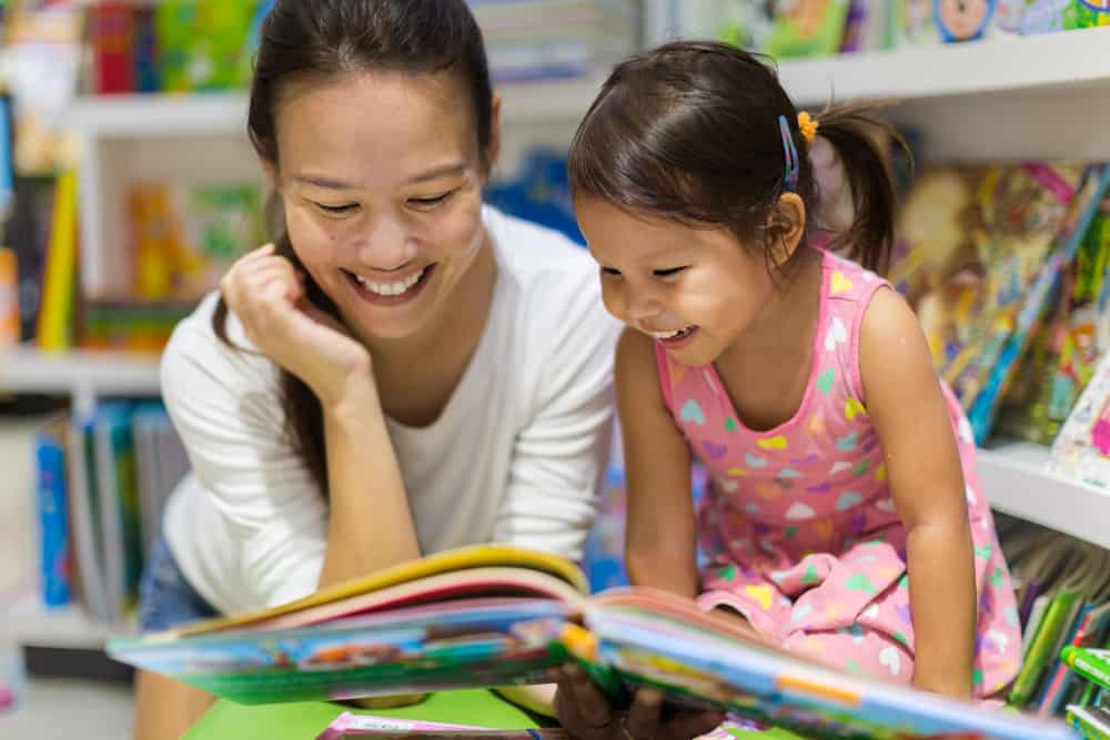 mom and toddler looking at books together