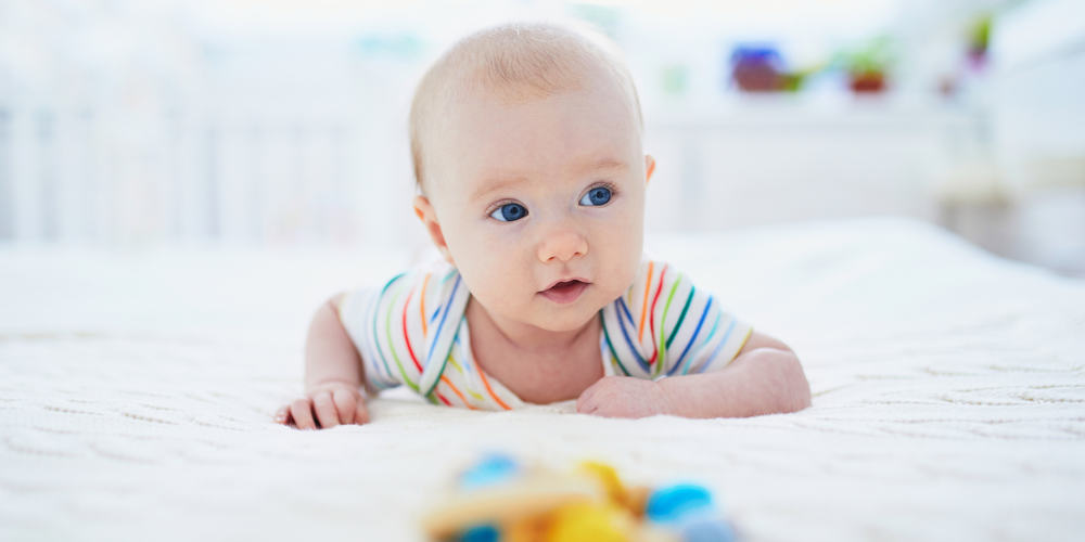 Baby girl learning to crawl. Little child doing tummy time. Infant kid in sunny nursery