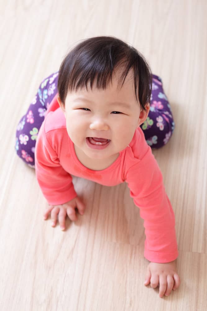 crawling baby girl on living room floor and she smile to you, asian child