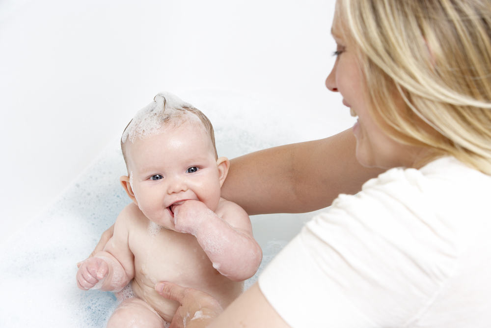mom bathing a smiling baby