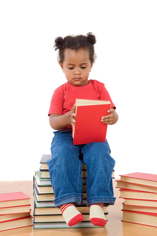 Adorable african baby reading sitting on a pile of books on a over white background