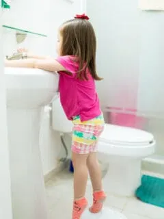 child washing hands in sink