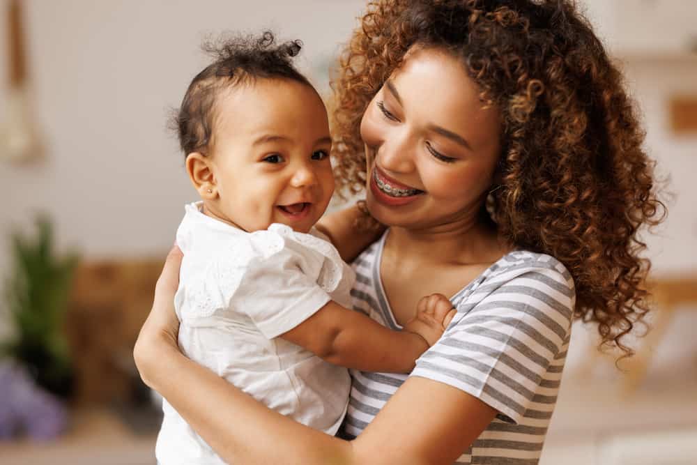 Happy, cheerful african american mother holds a laughing baby daughter in her arms. Concept of motherhood and a loving family