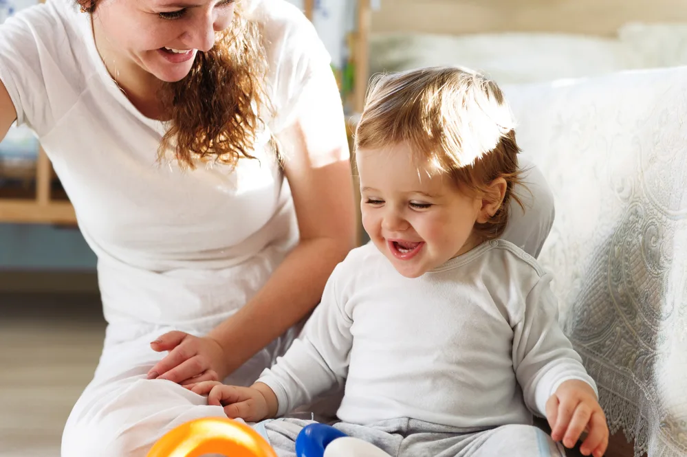 Young mother playing with her baby son at home