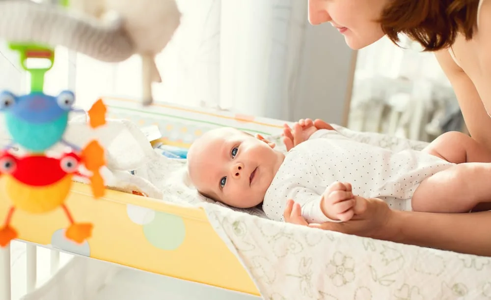 Mother gently care of baby on the changing table at home