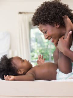 mom changing baby's diaper and making it fun