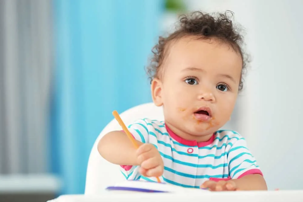 Little baby eating puree indoors