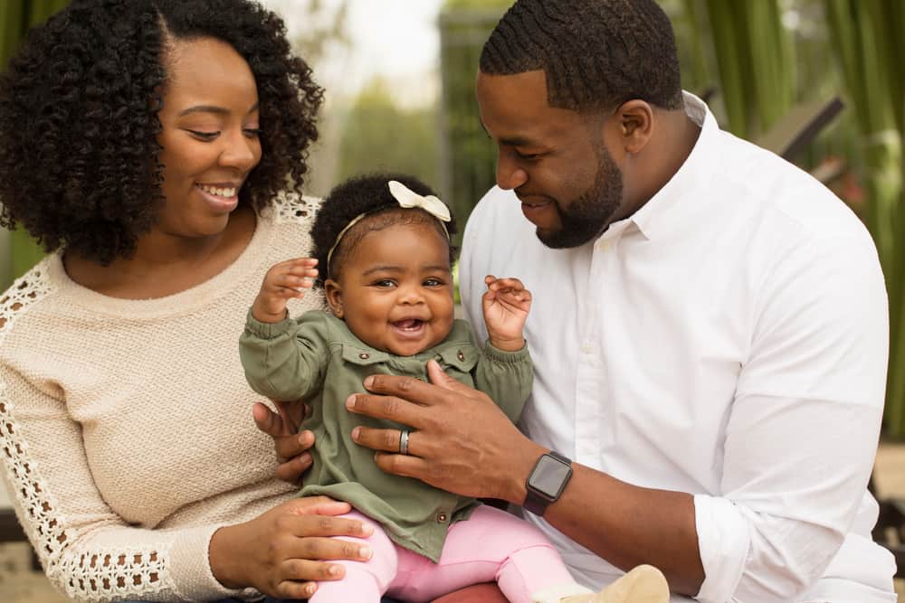 African American Family playing and laughing with their daughter.