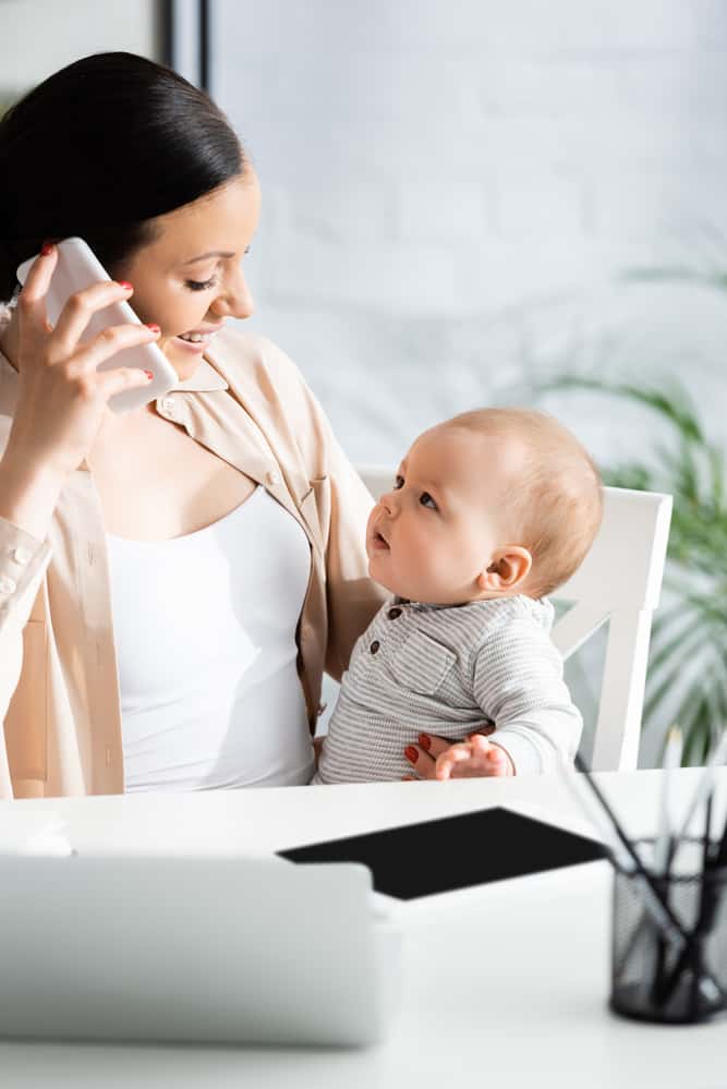mom on phone while holding baby