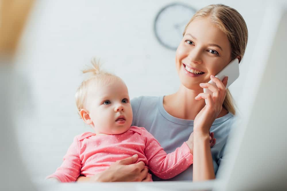 mom on the phone while holding a baby