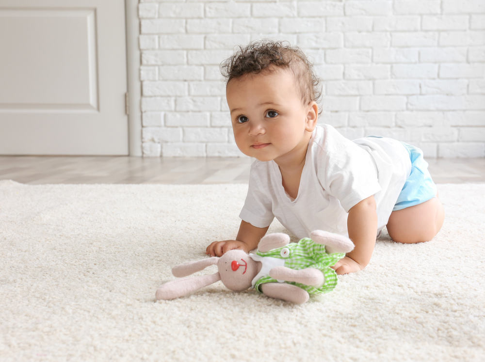 Adorable little girl playing on carpet with bunny