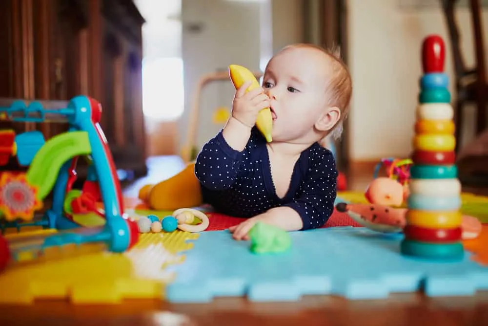 Baby girl playing with toys on the floor. Happy healthy little child at home