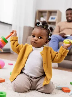 childhood and people concept - little african american baby girl playing with toy blocks at home