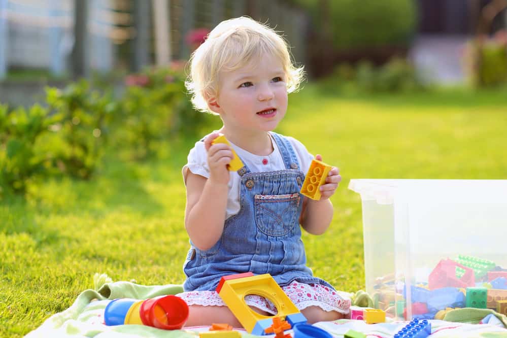 toddler playing with blocks in the backyard