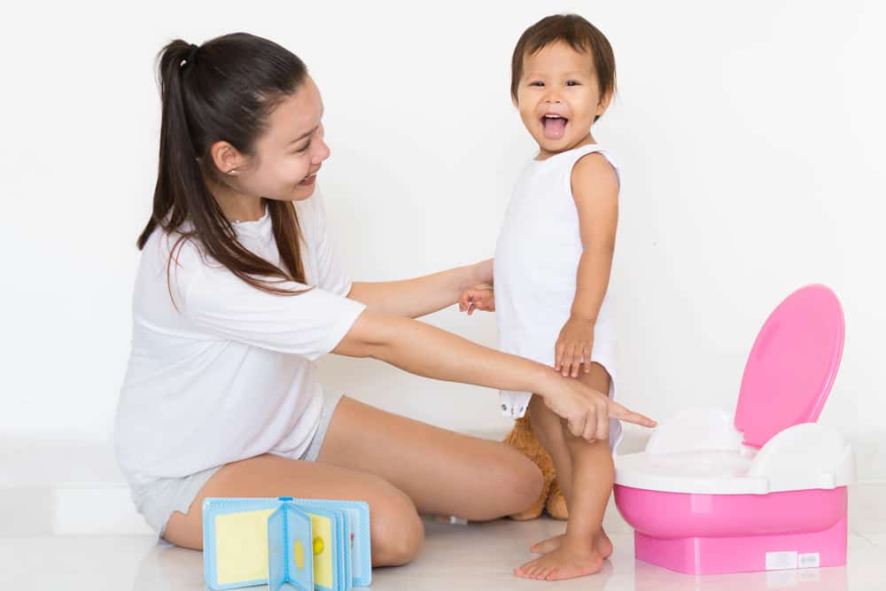 mom pointing at potty chair with toddler